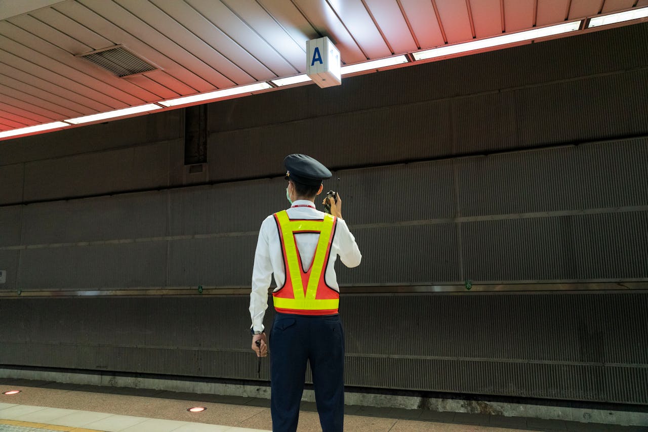 A security guard communicates via radio in an empty train station.